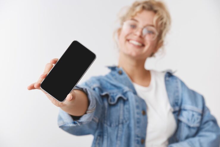 charming lucky goodlooking energized young blond caucasian girl blurred stretch hand show camera smartphone display promoting phone application gadget standing white background 176420 55485